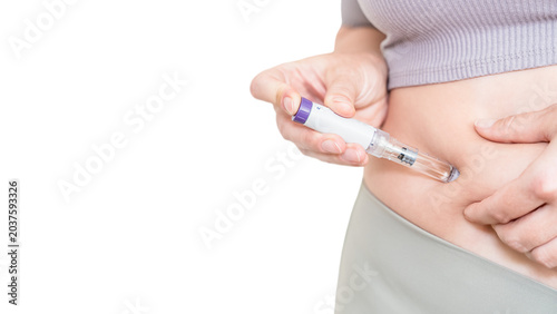 Woman injecting GLP-1 weight loss medication into stomach isolated on light background