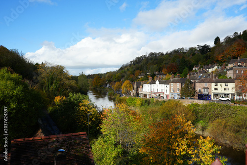 Picturesque Ironbridge Village With Traditional Buildings Lining The River Severn Amidst Vibrant Autumn Foliage In Shropshire, England