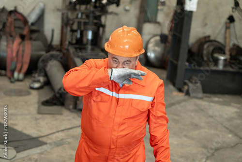 Construction worker wiping sweat from his face in a factory