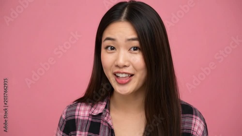 Curious Young Asian Woman Cupping Hand to Ear Eavesdropping on Pink Background