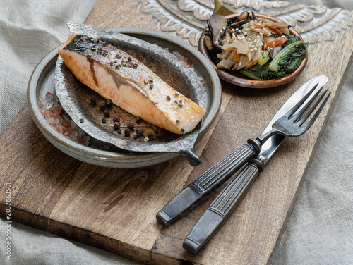 Salmon Shioyaki is a Japanese classic. Salt-grilling creates a savory, firm fillet with perfectly crispy skin. The fish features a vibrant coral hue and a delicate, flaky texture. It rests in a hand-c
