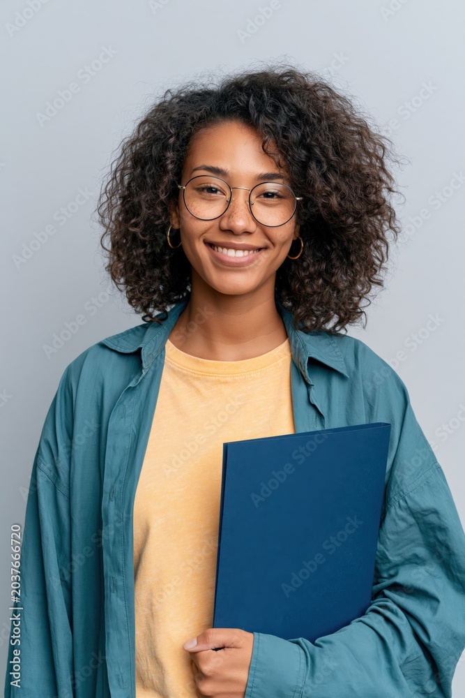 Obraz premium Smiling young college student holding a folder against a neutral background for education profile portrait and student branding