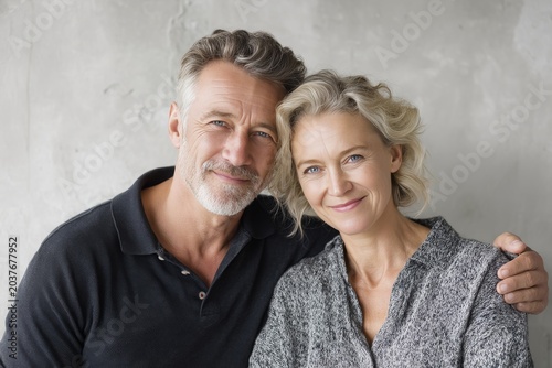 Portrait of a satisfied couple in their 50s donning a classy polo shirt in minimalist or empty room background