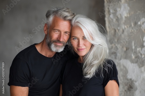 Portrait of a happy couple in their 60s dressed in a casual t-shirt isolated on empty modern loft background