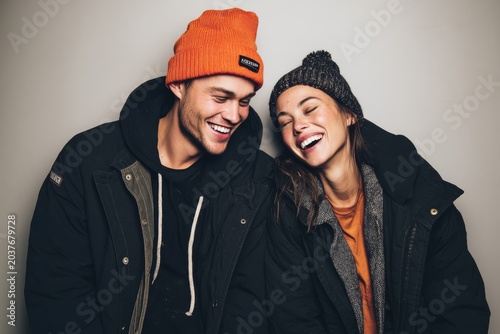 Portrait of a grinning caucasian couple in their 20s sporting a trendy beanie in plain cyclorama studio wall