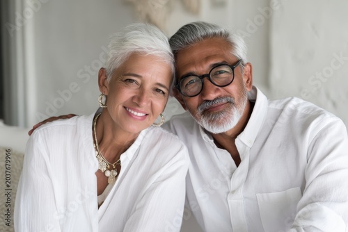 Portrait of a content latino couple in their 60s wearing a classic white shirt in crisp minimalistic living room