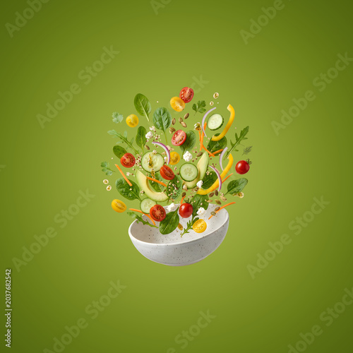 Fresh vegetables flying out of bowl on green background