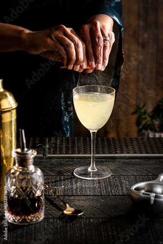 A hand squeezing a lemon over a cocktail