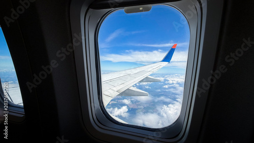 Foto Airplane wing visible through aircraft window with blue sky and clouds in the ba