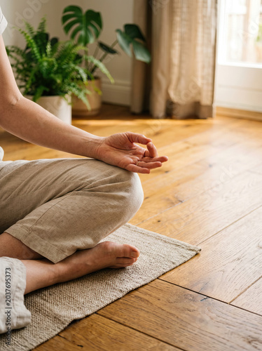 Meditation yoga practice indoors on wooden floor with natural light and green plants creating calm digital detox moment for mindfulness and relaxation in cozy home environment