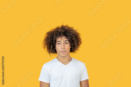 Portrait beautiful men of mixed race on a yellow background. A young ethnic man with curly hair in a white t-shirt looks relaxed .Beautiful young multiracial man