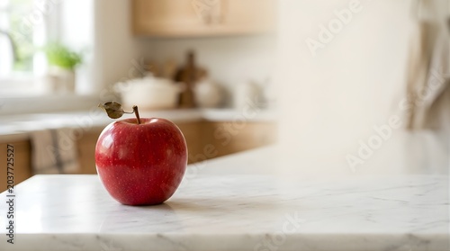 Fresh red apple sitting on a marble kitchen counter with blurred background