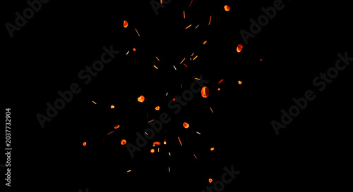Flying embers and sparks on black background illuminating a dark and dramatic scene