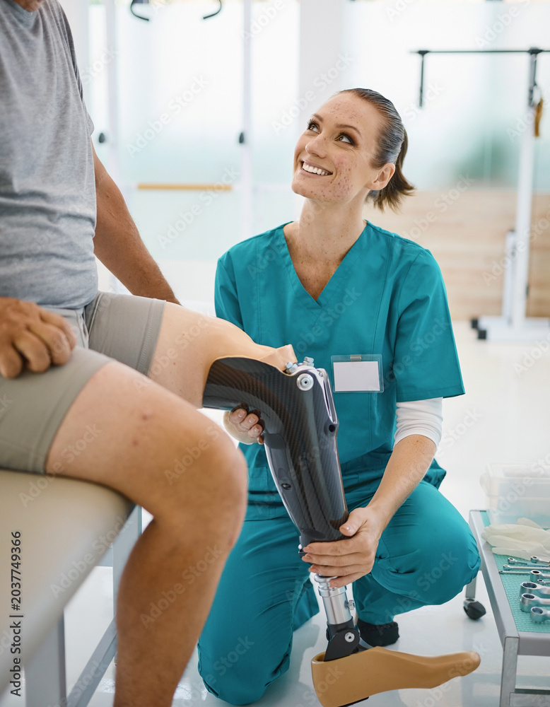 Naklejka premium Therapist woman adjusting prosthetic leg for patient at clinic