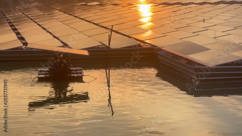 Floating solar panels and solar-powered water aerator on a lake during a golden sunset, renewable green energy footage