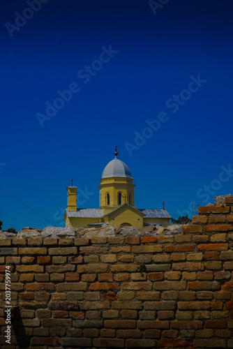 photo of a beautiful church with a yellow facade above which is a blue sky