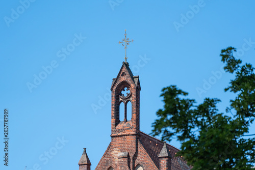 Fotografía A brick church roof and small cross stand beneath a clear blue sky