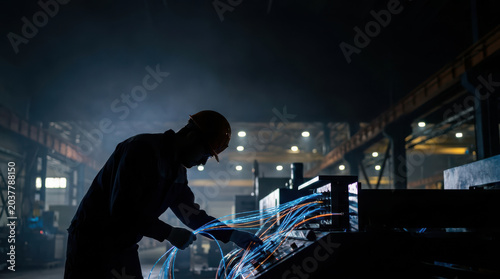 Technician working with fiber optic cable in dark industrial factory with glowing blue light