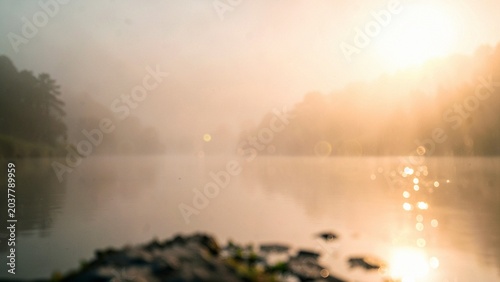 Stone foreground overlooking misty golden lake at sunrise atmospheric landscape