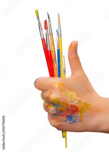 Hand shows thumbs up while holding paintbrushes with colorful paint on fingers