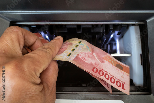 Schilderij op canvas A hand withdrawing money, Rupiah from cash machine, in Indonesia