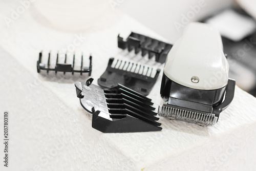 Home barbering kit; hair clipper and guide combs on a white surface