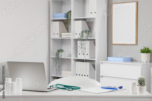 Doctor's workplace with laptop, stethoscope and pills in medical office