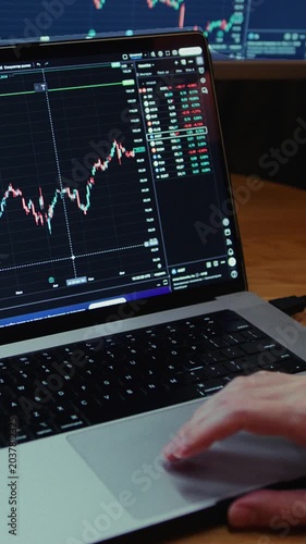 Man trader monitors market charts on laptop, screen and smartphone at home. Analyzing real-time trading data, considering investment strategies. Professional investor engaged in day trading, Evening