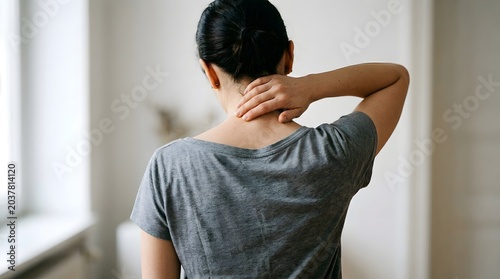 Woman with neck pain looking stressed or uncomfortable indoors
