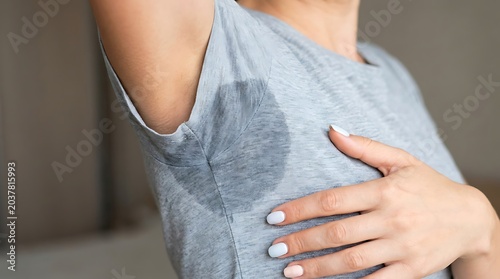 Close up of woman wearing gray t-shirt with large underarm sweat stain highlighting hyperhidrosis and body perspiration, t shirt