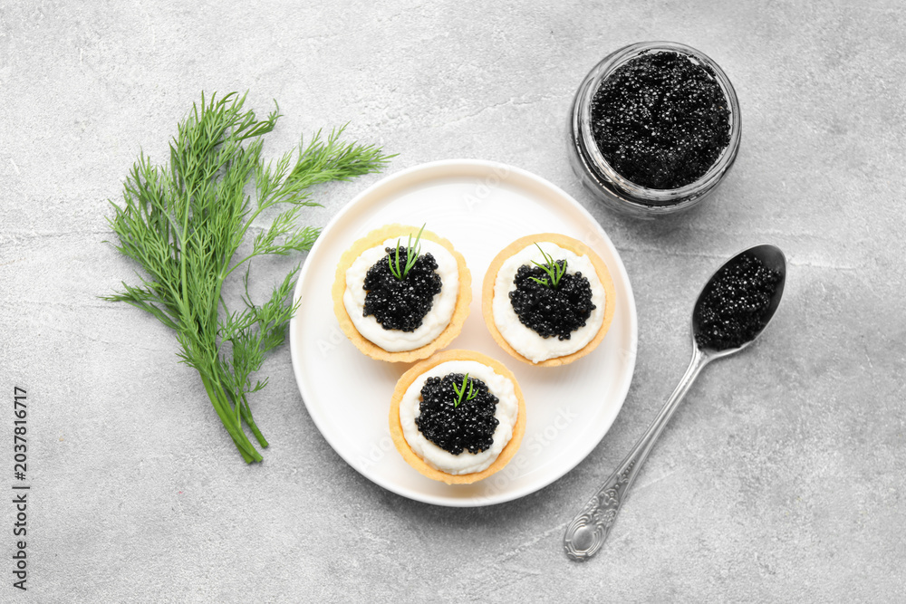 Obraz premium Tasty tartlets with black caviar, cream cheese and dill on light grey table, flat lay