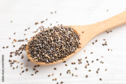 Natural chia seeds in spoon on white wooden table  closeup