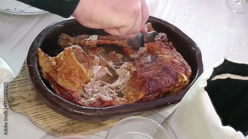 Corte y deshuesado de sabroso lechazo, cordero joven,  asado al horno de leña en cazuela de barro, provincia de Valladolid, España
