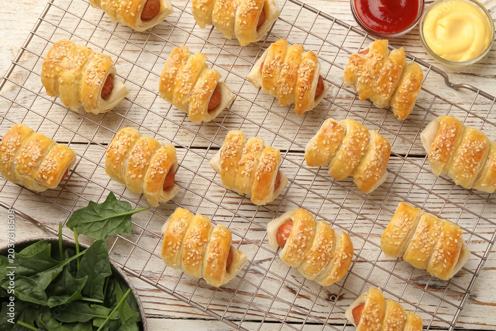 Obraz premium Puff pastry. Tasty sausages in dough and sauces on white wooden table, flat lay