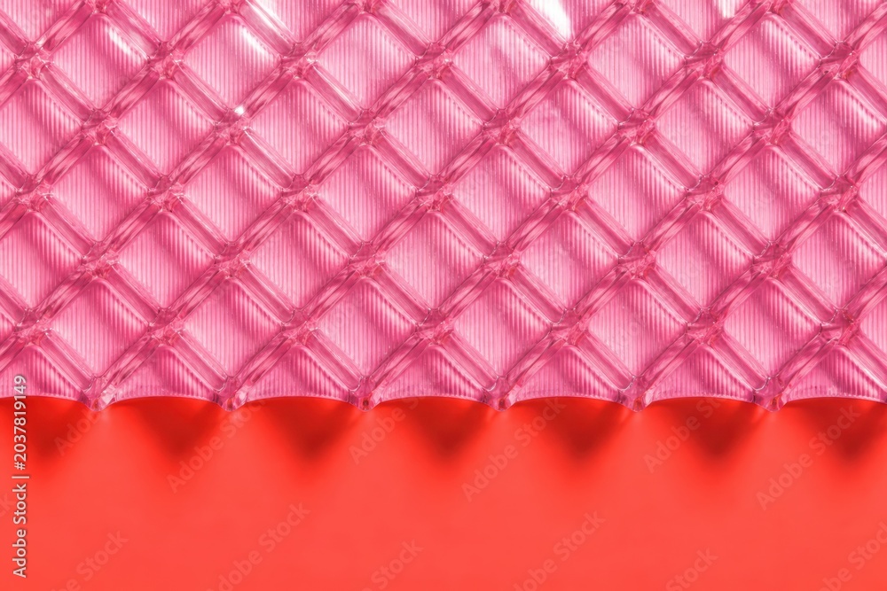 Naklejka premium Pink quilted textile texture with diamond pattern over red background in soft abstract close up