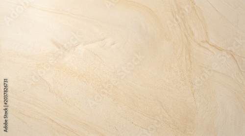 Closeup of beige sandstone texture with natural wavy patterns and granular surface