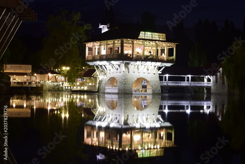 Vászonkép Beautiful restaurant building illuminated at night with perfect reflection in th