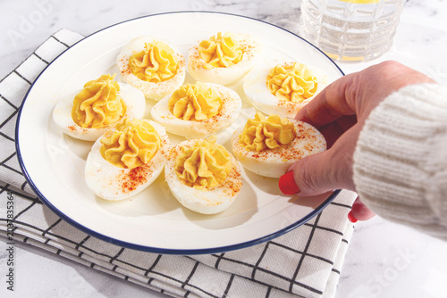 stuffed eggs with paprika, on a plate, a woman's hand reaches for it,