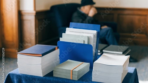 Closeup of pamphlets and brochures neatly arranged on a table display with a pension expert conversing softly in the unfocused background.