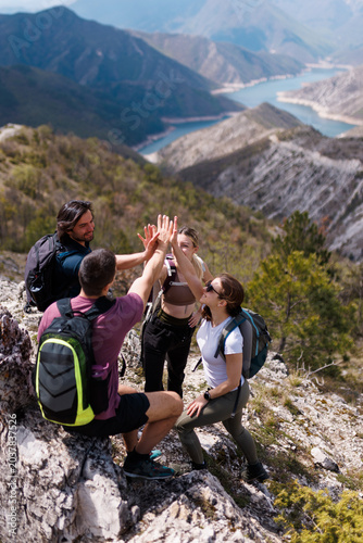 Bild auf Leinwand Group of friends hiking in the mountains celebrating with a high five on a rocky