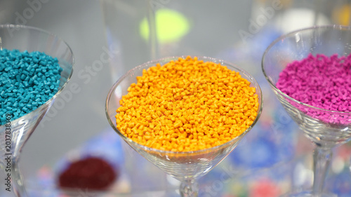 Vibrant yellow plastic masterbatch pellets stored in clear glass containers.