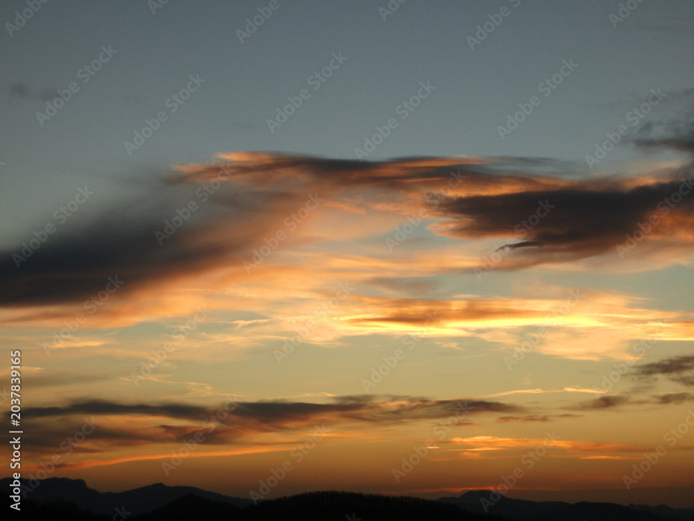 Fototapeta premium Atardecer con nubes en el cielo y montañas