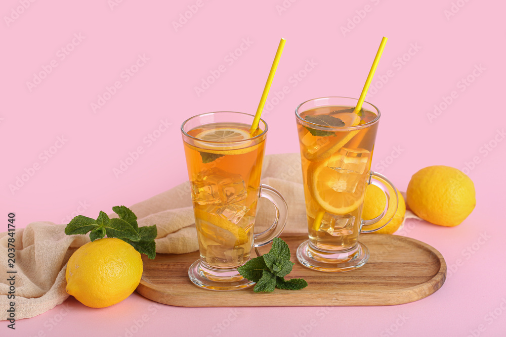Fototapeta premium Glass cups of lemon ice tea with mint and citrus fruits on pink background
