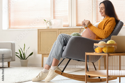 Young pregnant woman knitti...