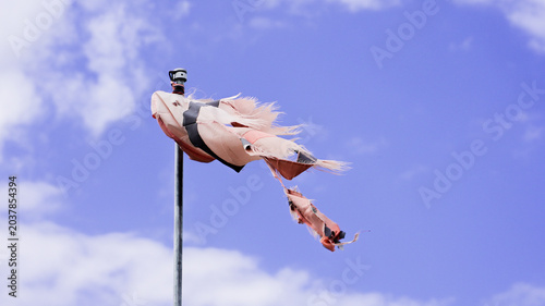 Tattered windsock fluttering with frayed fabric against blue sky