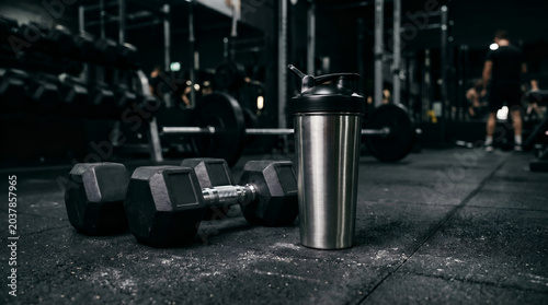 Fitness gym equipment with dumbbells and bottle.