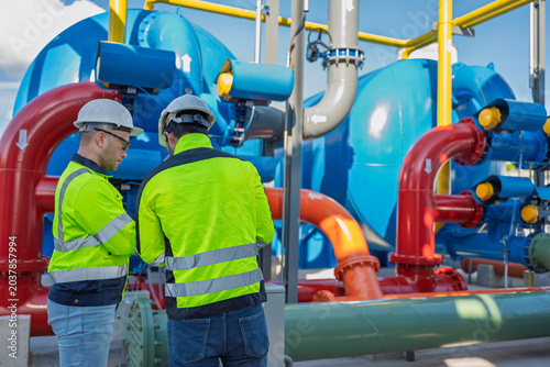 Foto Two industrial engineers inspecting automated pipeline valves at a modern water treatment facility
