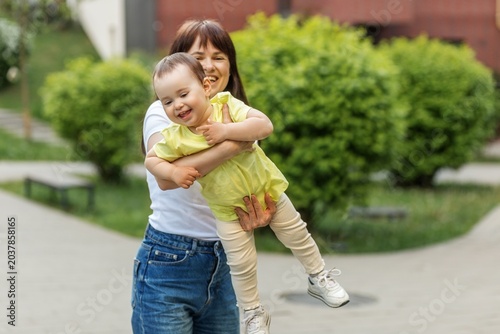 Mother Carrying Laughing Toddler Daughter Outdoors