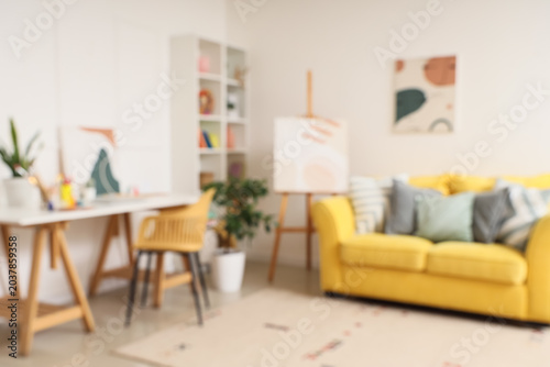 Blurred view of student's room with sofa, table and art supplies