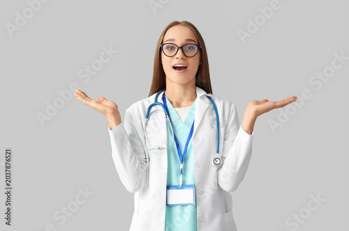 Surprised female doctor on light background